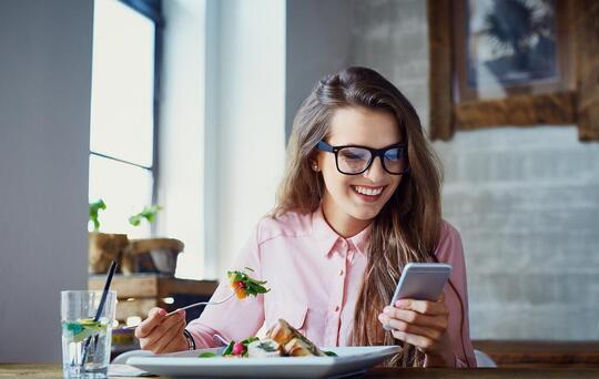 Jeune fille regardant son téléphone tout en mangeant